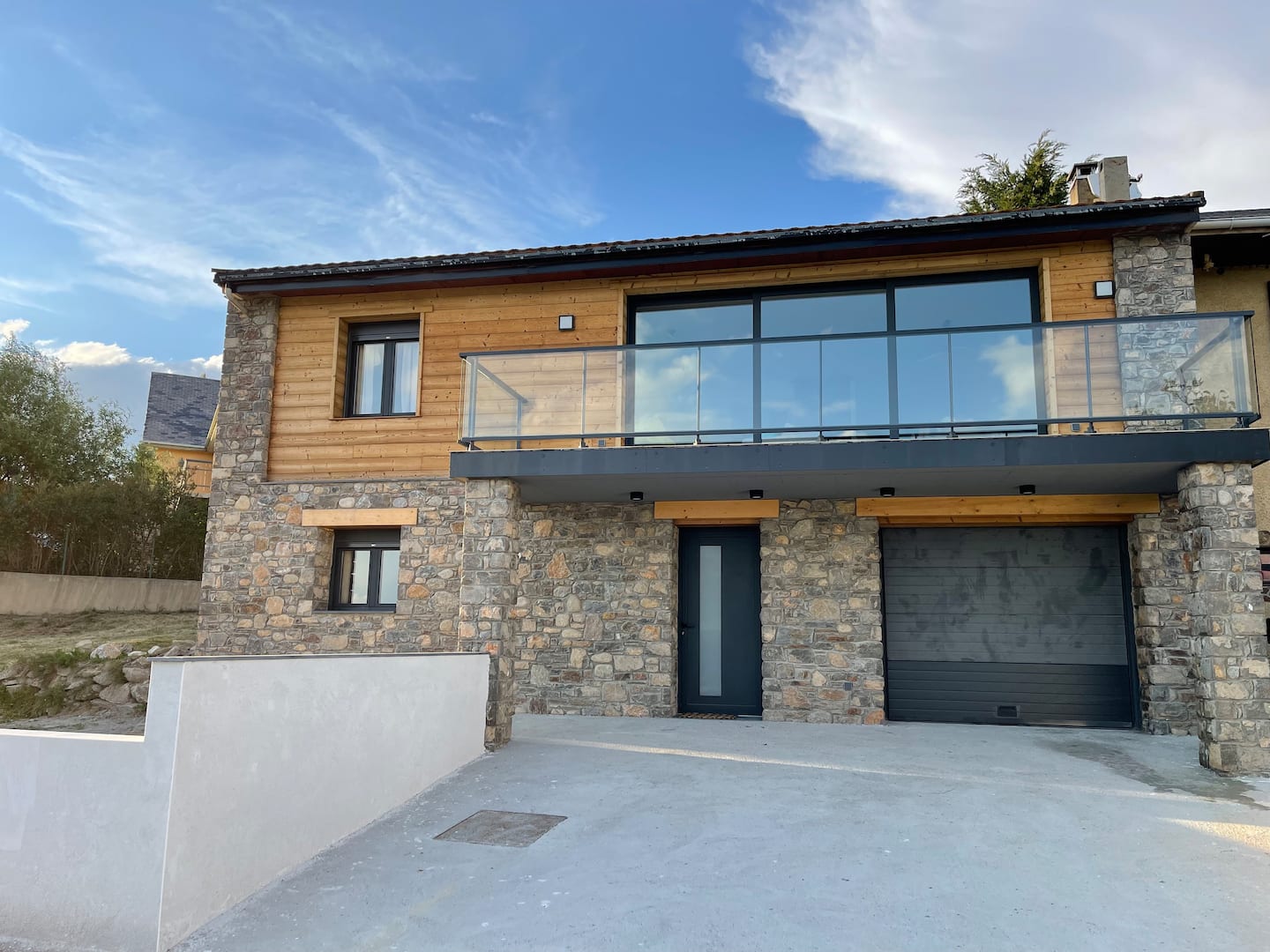 Façade en bois et pierre, avec l'entrée du garage